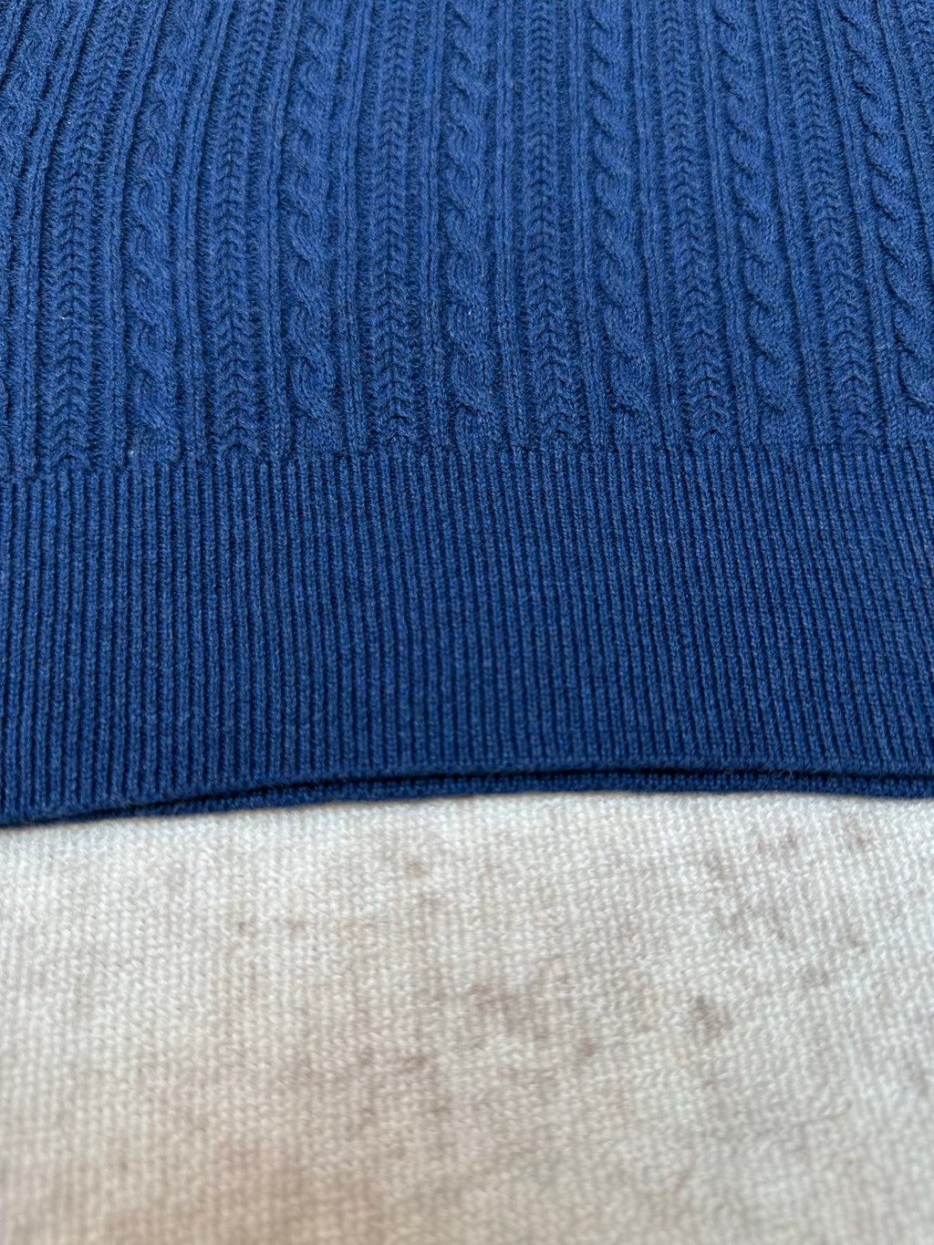 Blue knit polo shirt hem with ribbed trim and cable texture