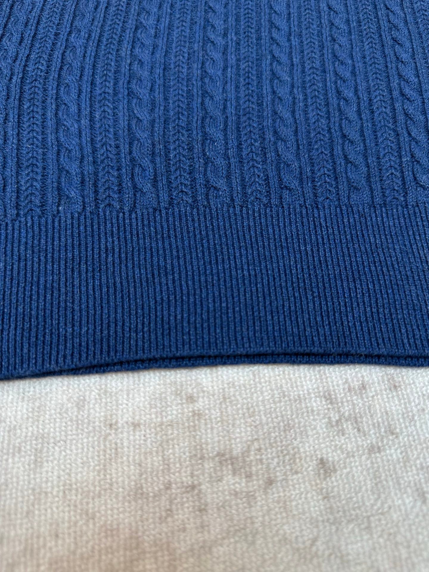 Blue knit polo shirt hem with ribbed trim and cable texture