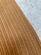 Tan cable-knit polo sleeve close-up with cable stitch pattern