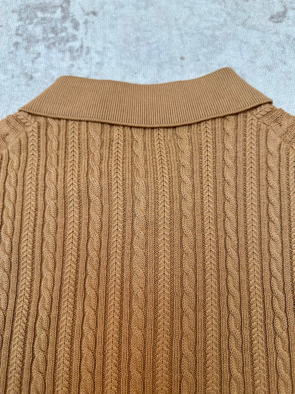 Tan cable-knit polo back with ribbed collar and vertical knit texture