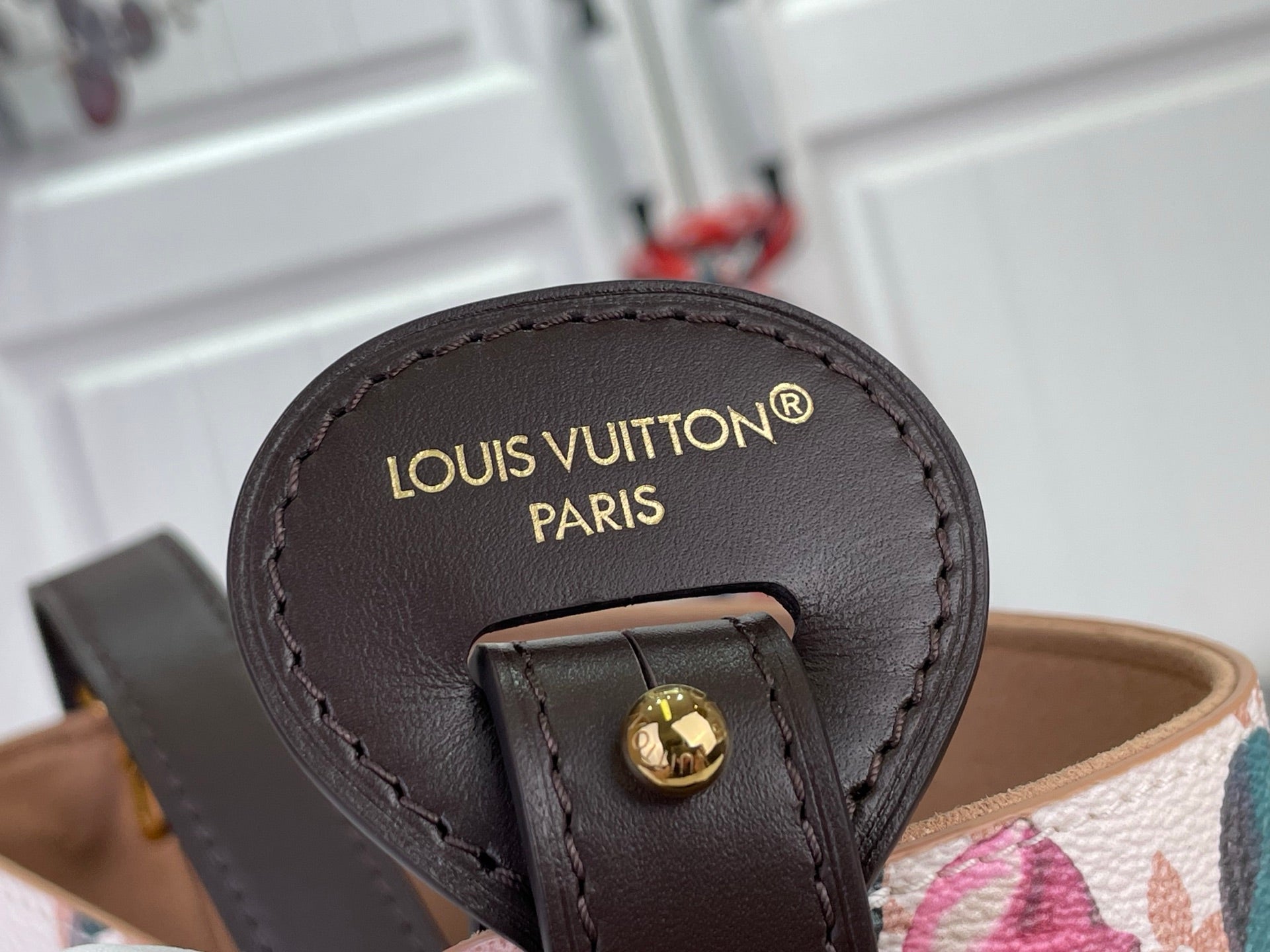 Louis Vuitton bag closeup of 'Louis Vuitton Paris' leather label on dark strap