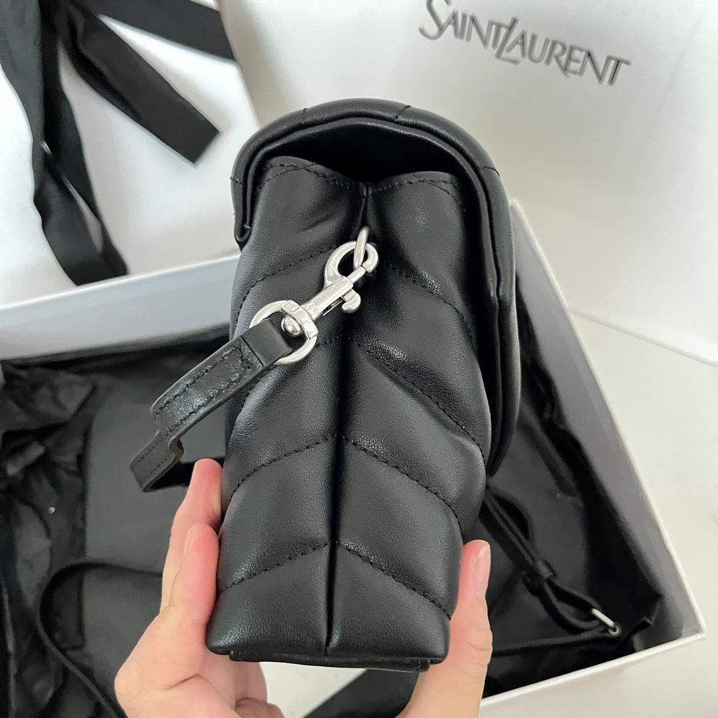 YSL bag side view with metal clasp, zip pull, and quilted dark leather panels