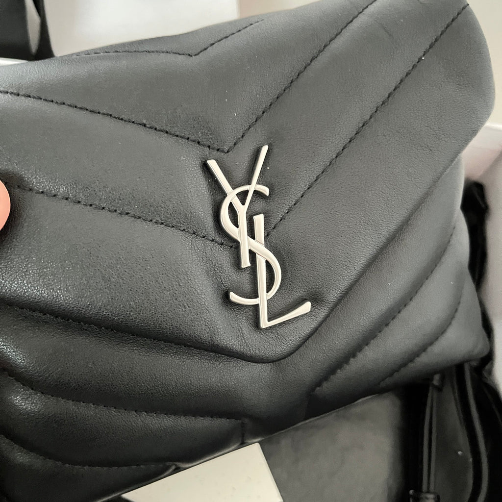 YSL bag close-up of YSL logo on dark quilted leather flap
