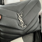 YSL bag close-up of YSL logo on dark quilted leather flap