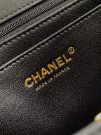 Chanel logo on textured black leather bag with visible stitching and seam