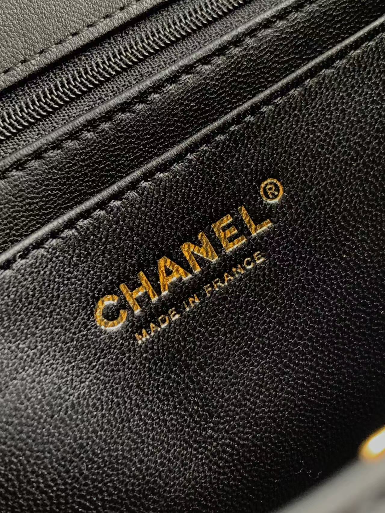 Chanel logo on textured black leather bag with visible stitching and seam