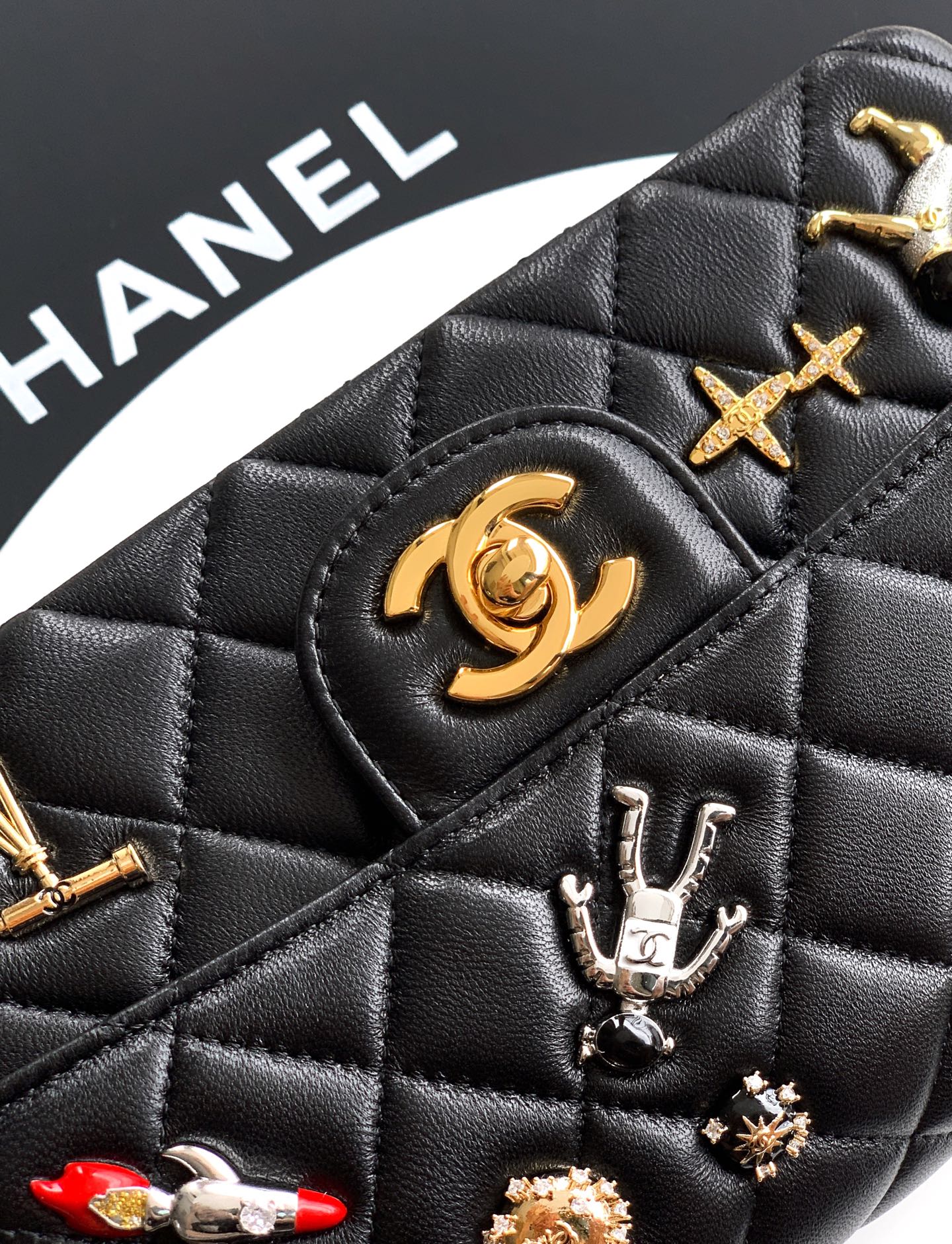 Chanel quilted black bag close-up with gold emblem and silver charm details