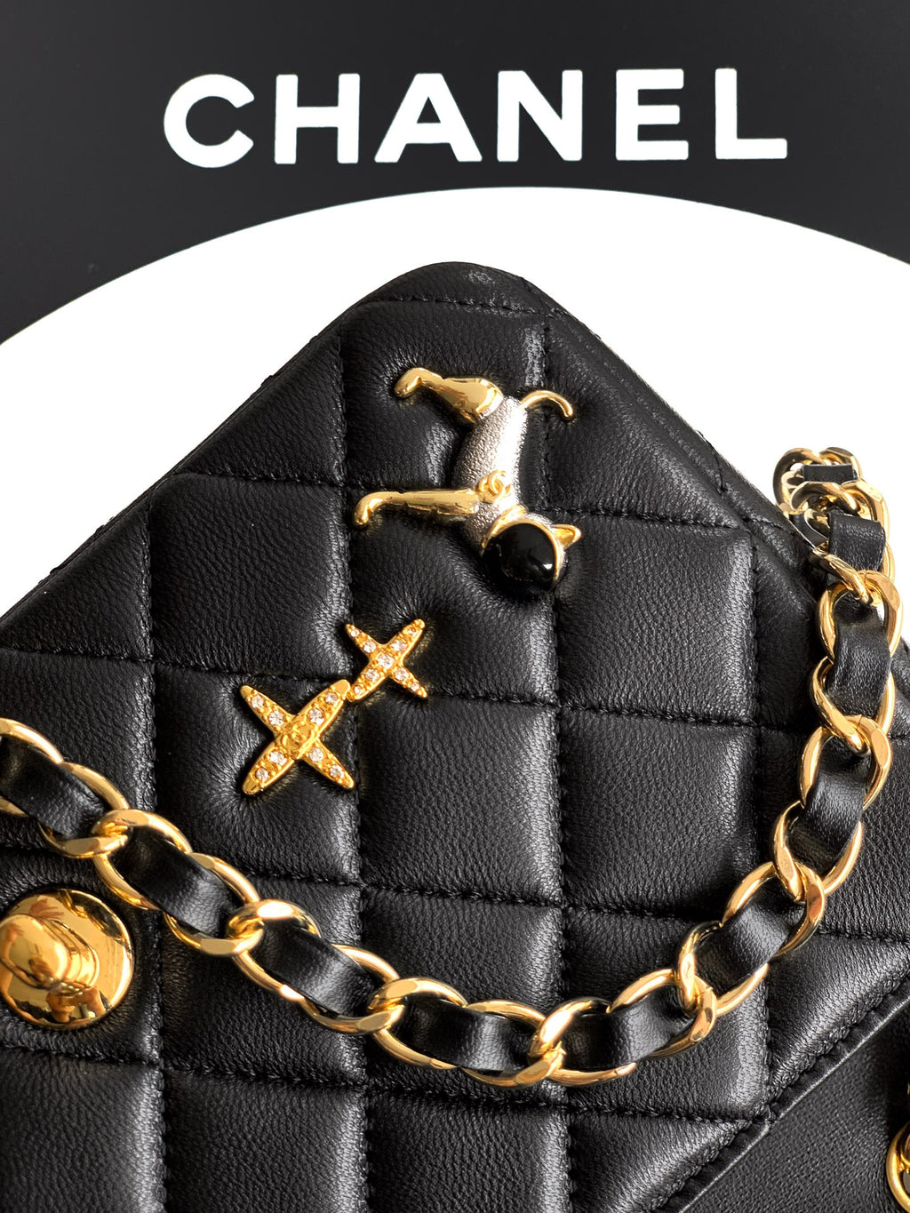Chanel quilted black bag front close-up with gold hardware and chain links