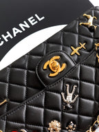 Close-up of Chanel quilted black bag with gold logo, charms, and hardware details