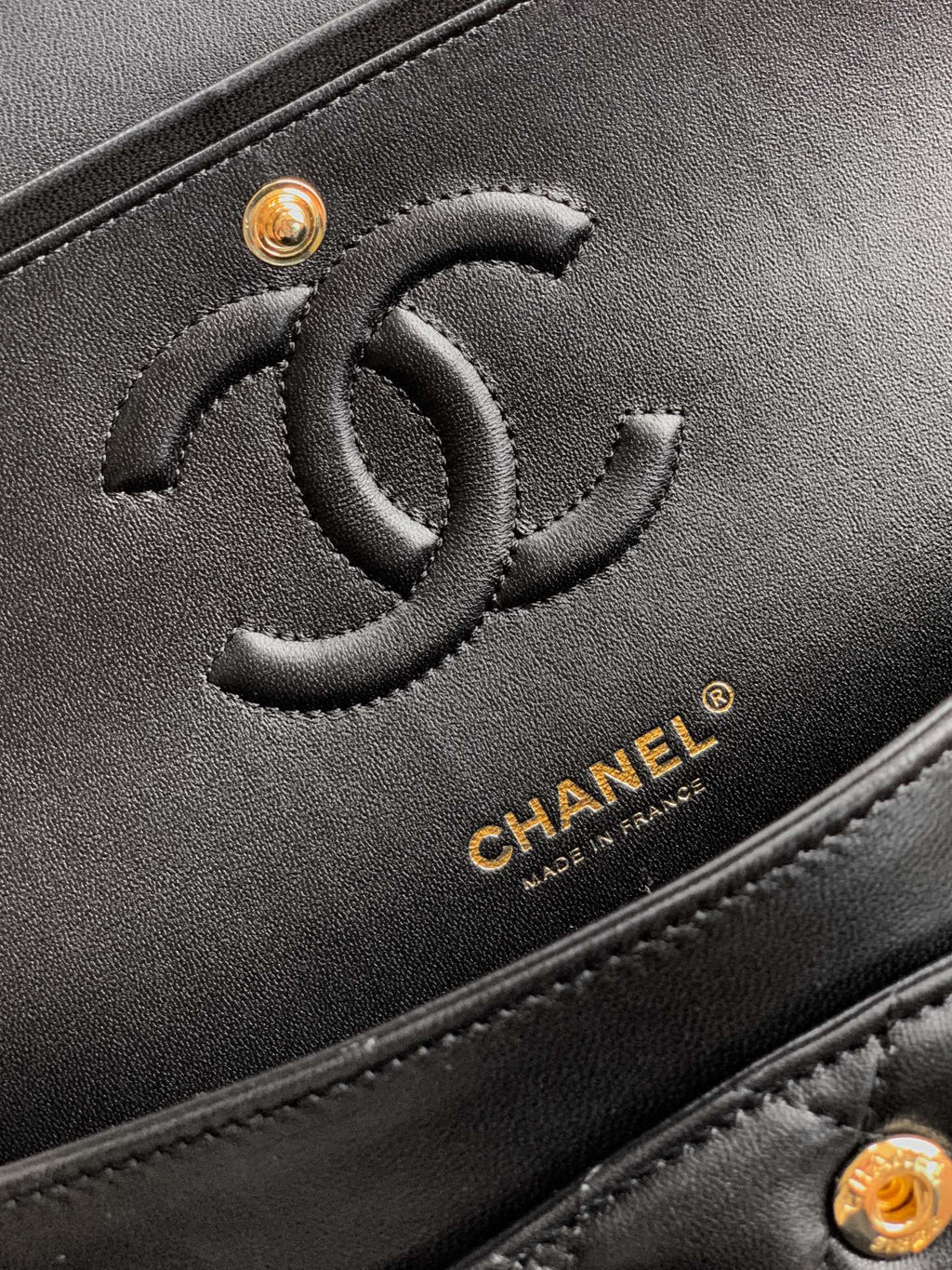 Close-up of Chanel black leather bag with embossed CC logo and gold hardware