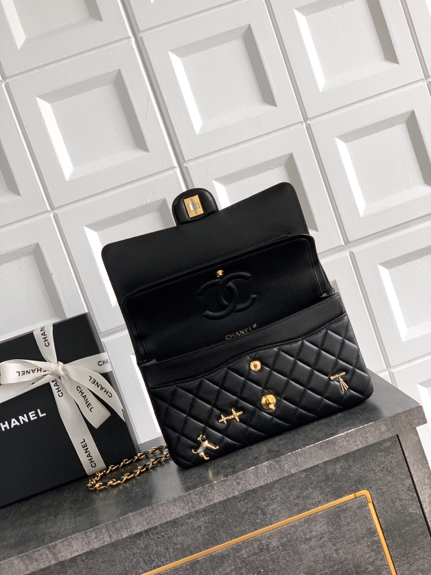 Black Chanel quilted flap bag with gold chain strap and decorative charms