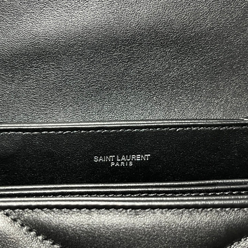 Embossed Saint Laurent Paris label on dark leather trim