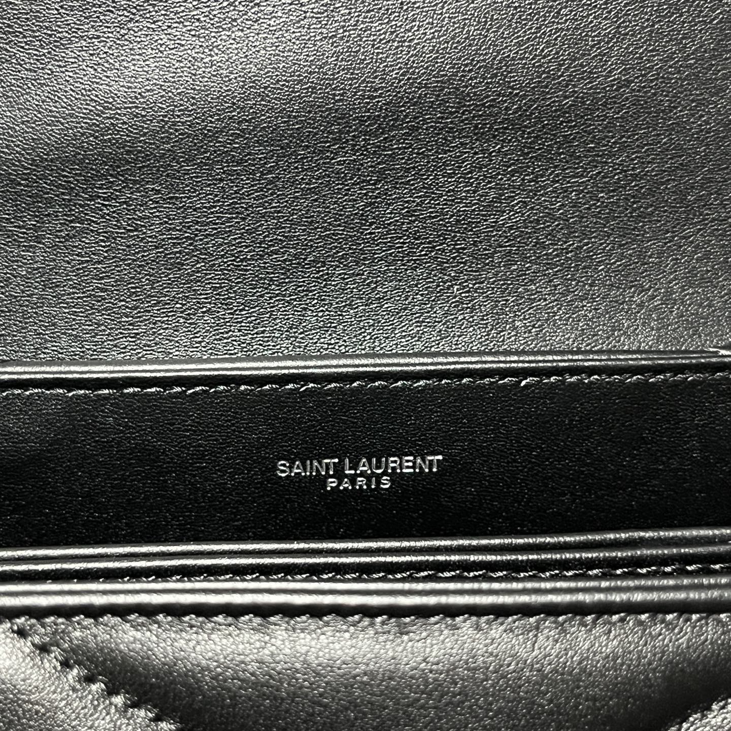 Embossed Saint Laurent Paris label on dark leather trim