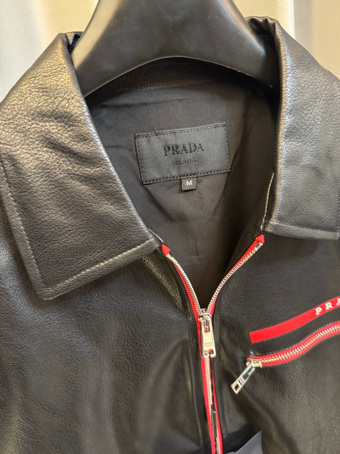 Prada black leather jacket neckline with red zipper and interior brand label