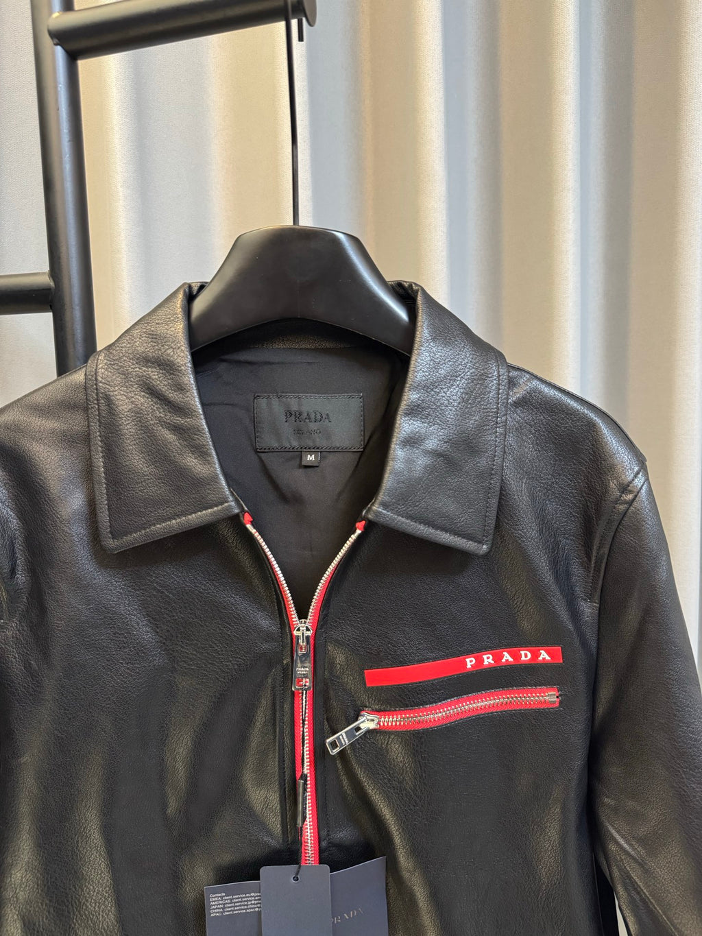 Prada black leather jacket with spread collar, red zip trim, and logo stripe