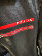 Close-up of Prada black leather jacket zipper and red logo stripe