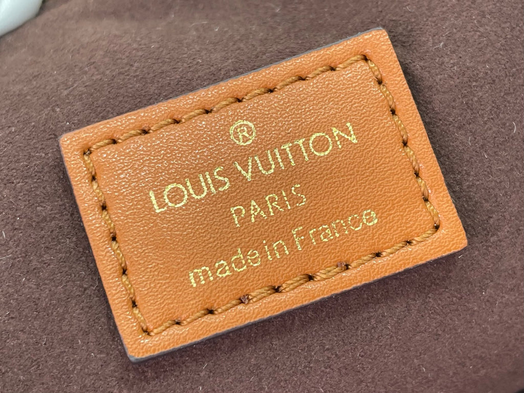 Tan leather Louis Vuitton bag label with gold logo, Paris text, and stitched edges