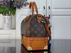 Monogram handbag with tan leather trim, curved top handle, and gold-tone hardware