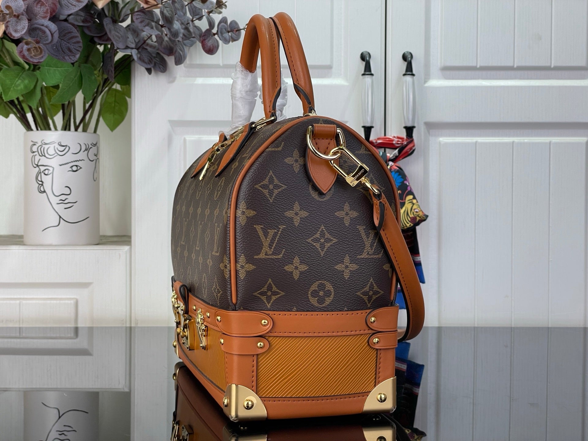 Monogram handbag with tan leather trim, curved top handle, and gold-tone hardware