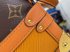 Tan leather strap attachment with gold-tone snap button on monogram canvas