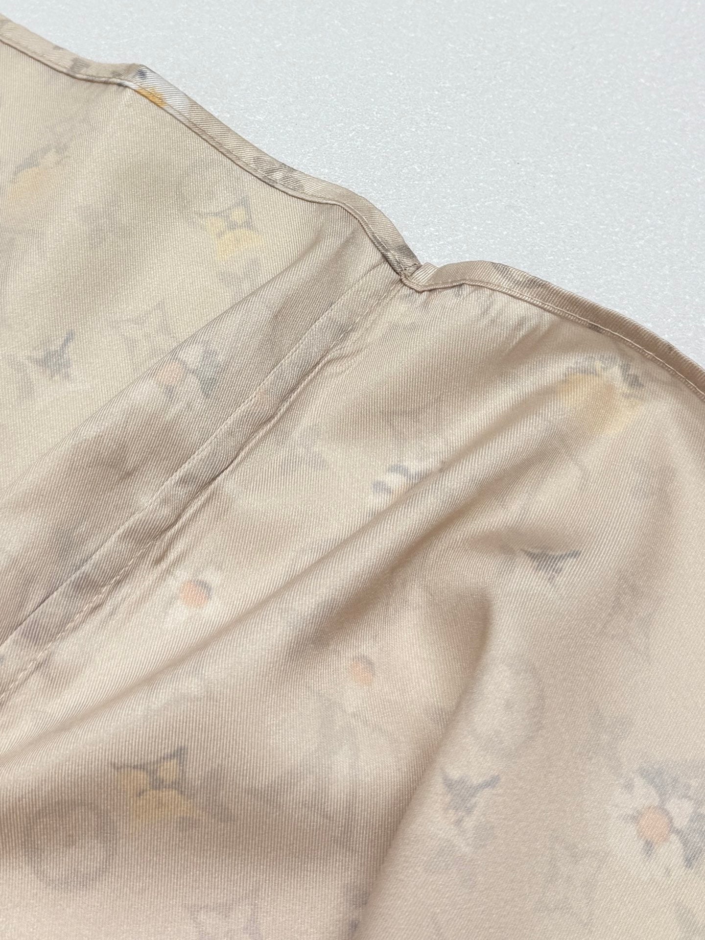 Beige short-sleeve shirt close-up of shoulder seam and monogram floral pattern
