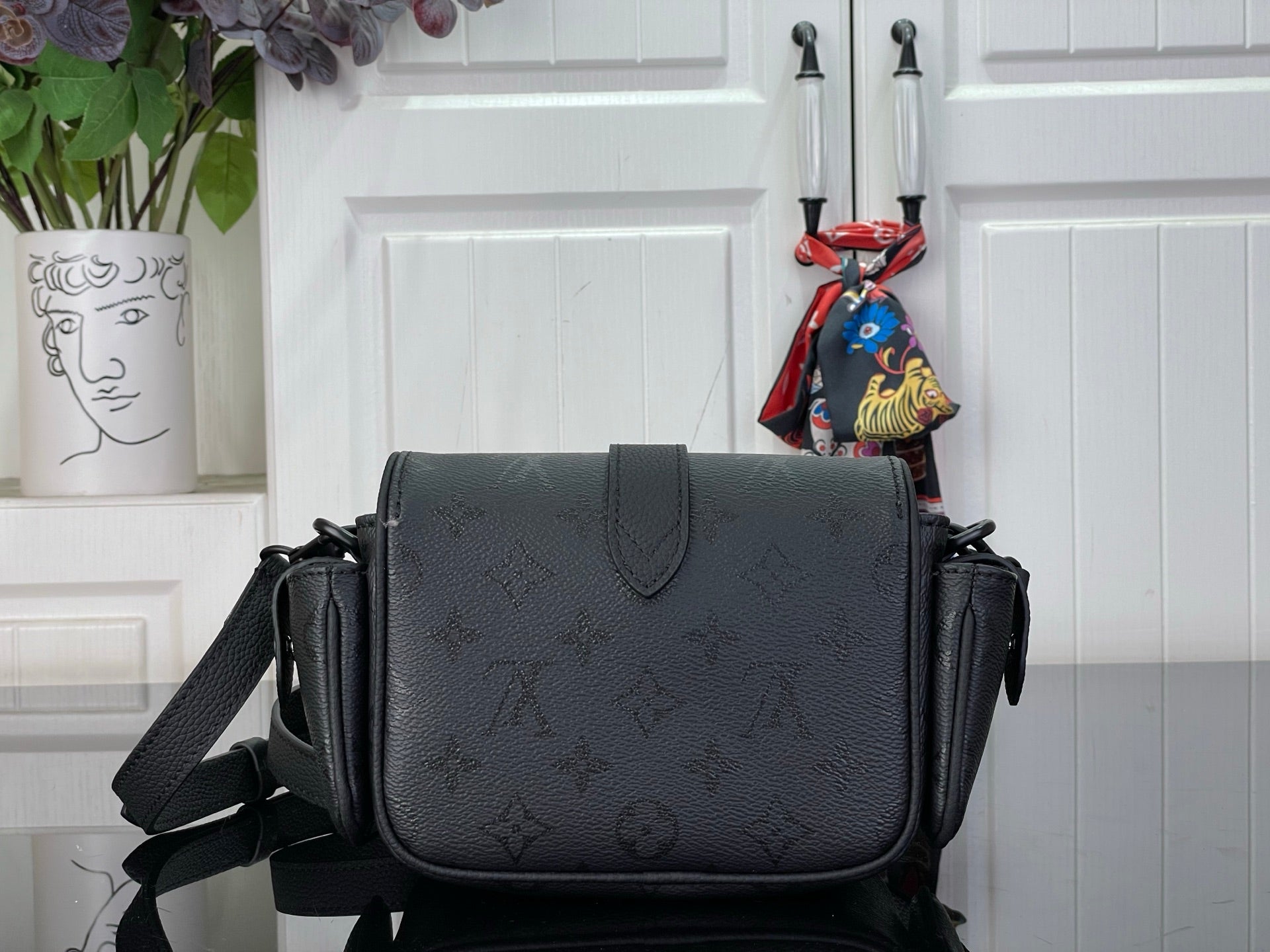 Louis Vuitton black crossbody bag with flap front and textured leather-look finish