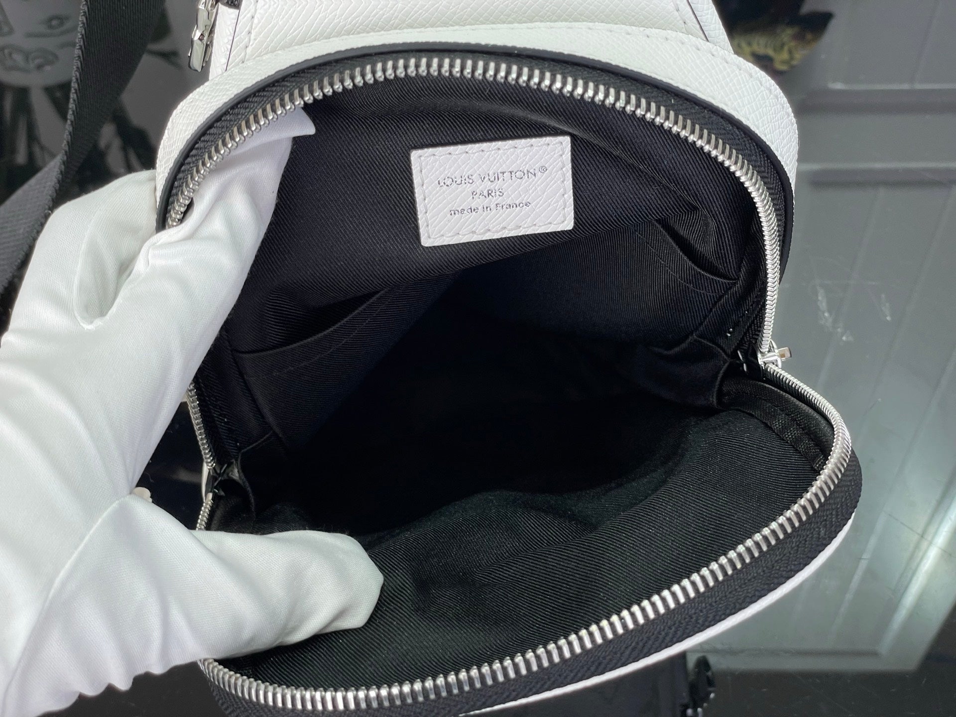 Open white Louis Vuitton monogram bag showing black fabric interior lining