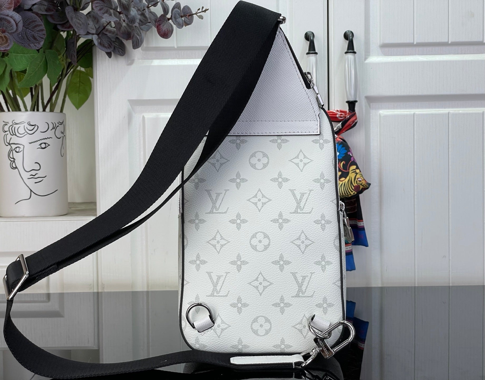 White Louis Vuitton monogram crossbody bag with black strap and metal side hardware