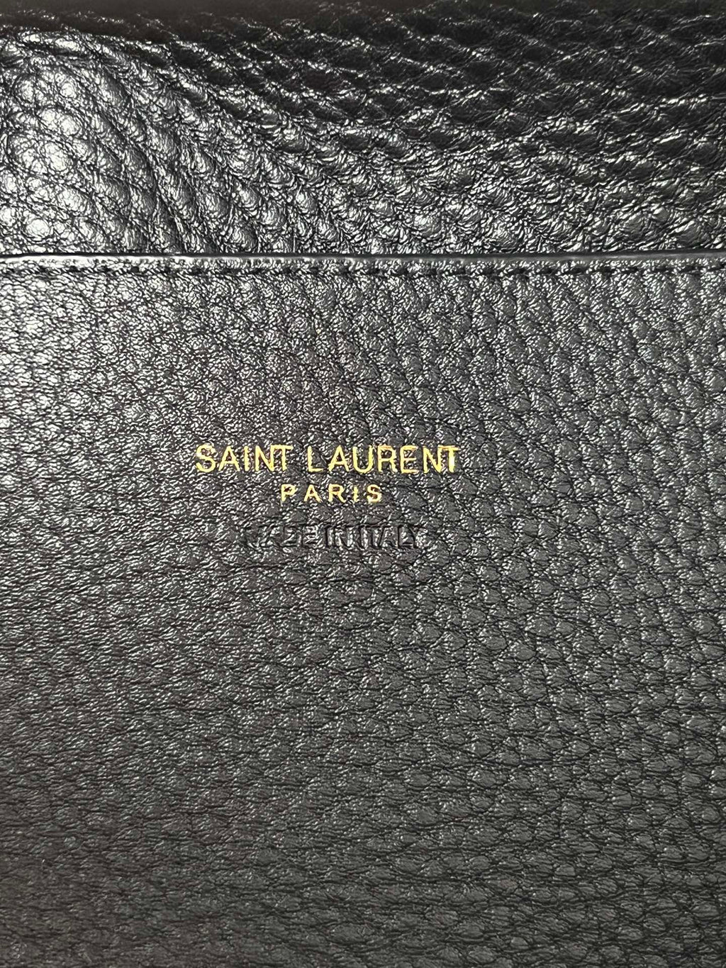 YSL leather mini tote bag close-up, black pebbled texture with branding stamp.