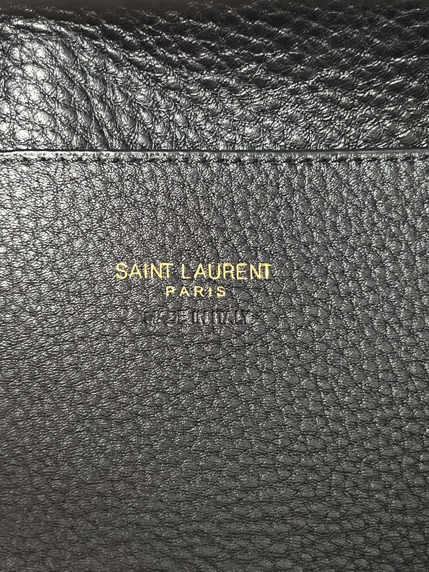 YSL leather mini tote bag close-up, black pebbled texture with branding stamp.