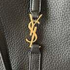 YSL logo clasp on black leather strap, gold-tone hardware detail.