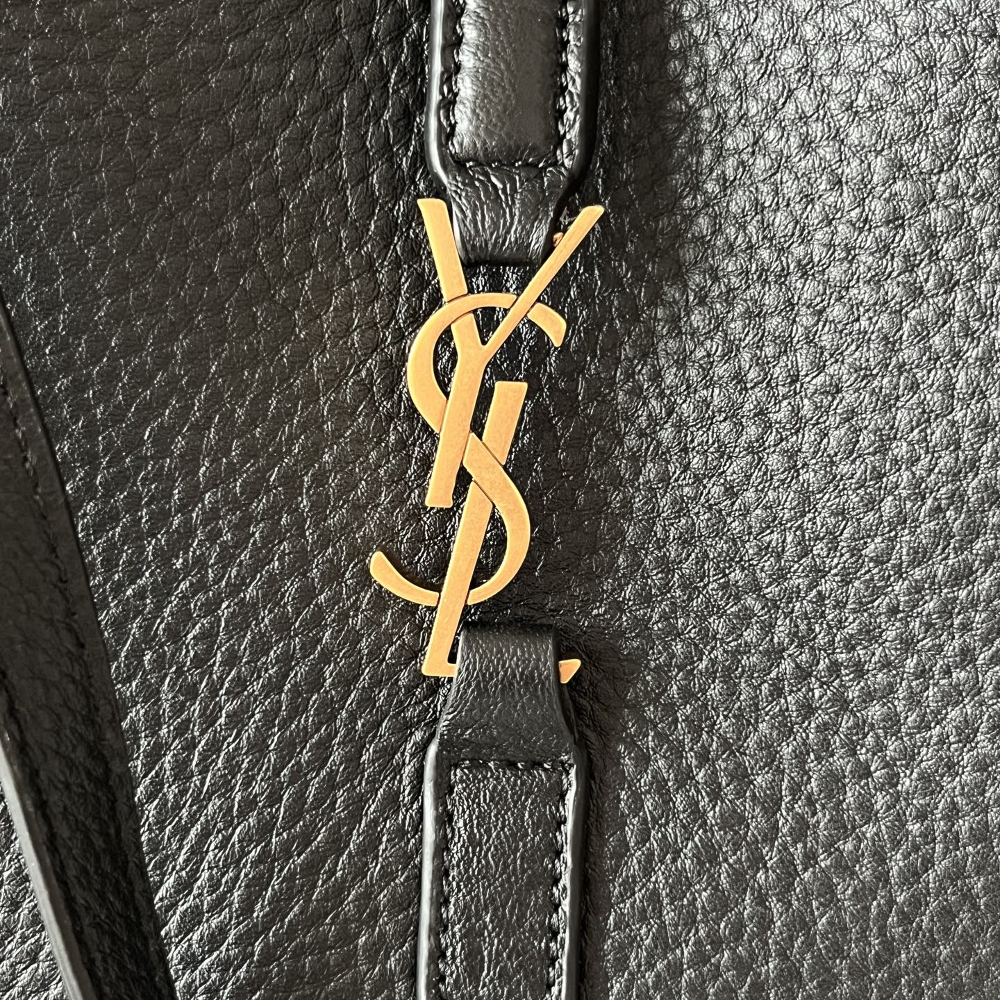 YSL logo clasp on black leather strap, gold-tone hardware detail.