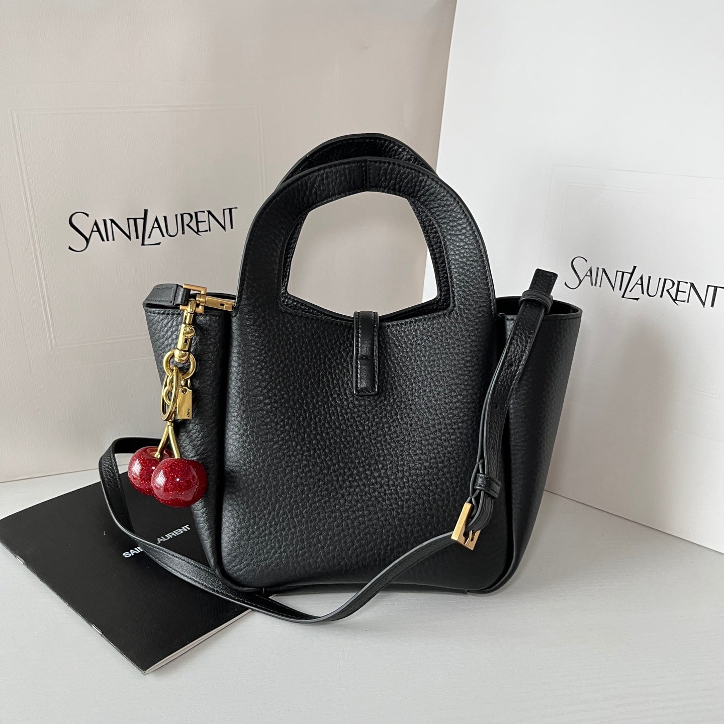 YSL leather mini tote bag in black, structured shape with gold-tone accents and charm.