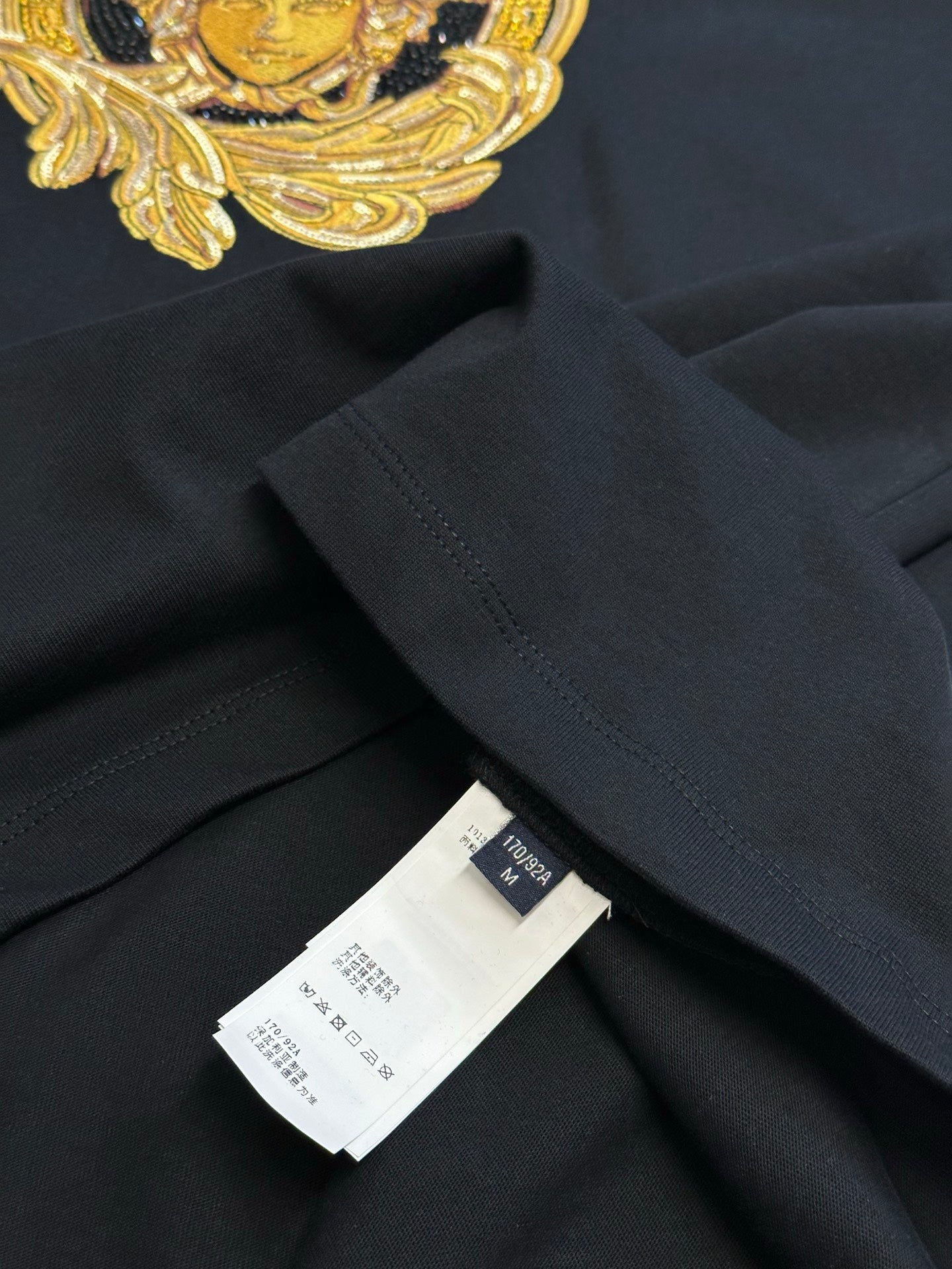 Versace black T-shirt hem with size tag and fabric label