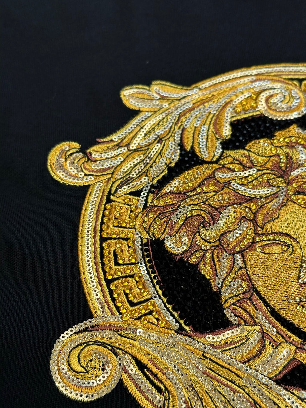 Versace black T-shirt close-up of gold Medusa profile design