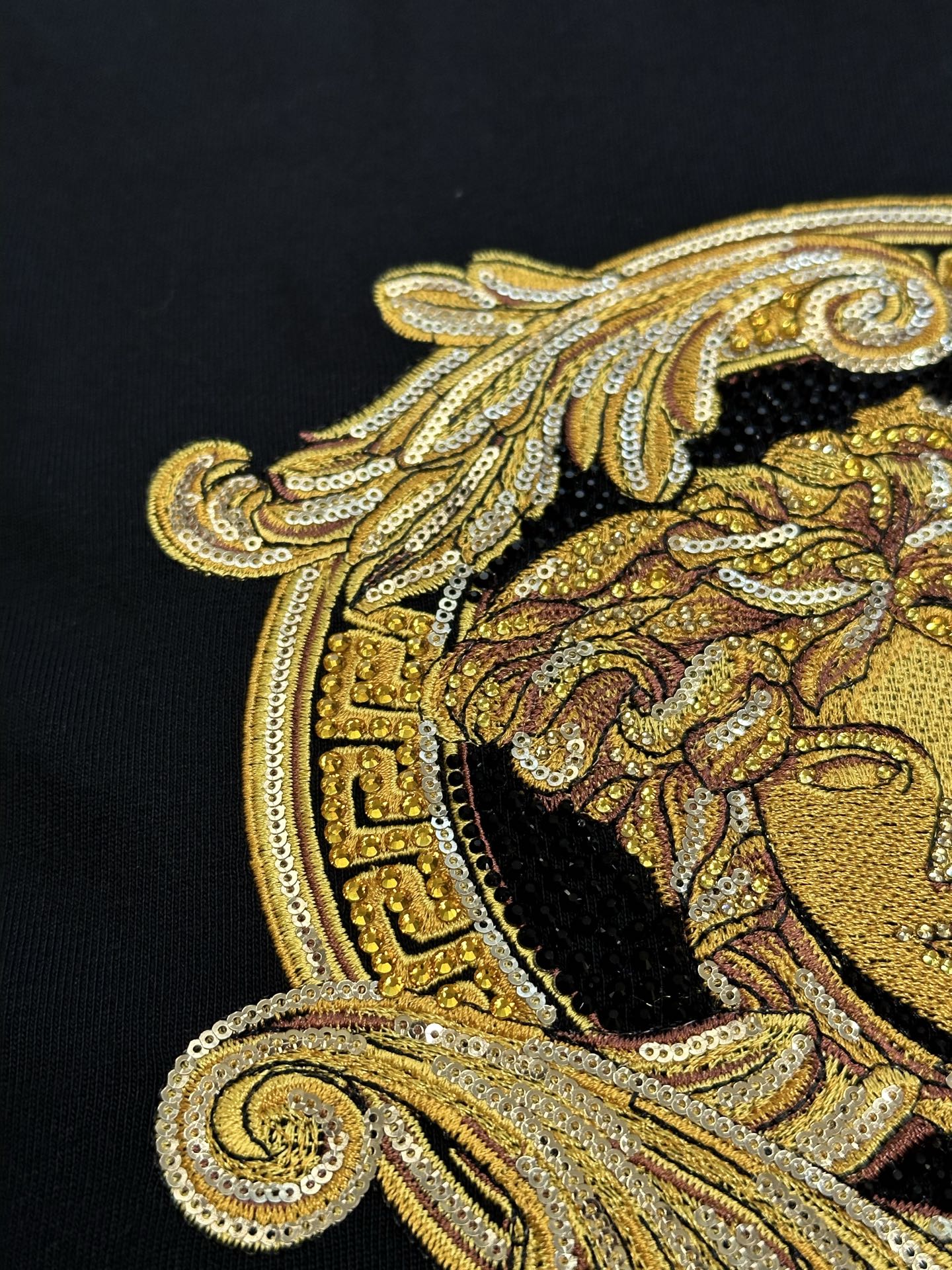 Versace black T-shirt close-up of gold Medusa profile design