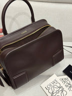 Dark brown leather top-handle bag with gold zipper and front seam details