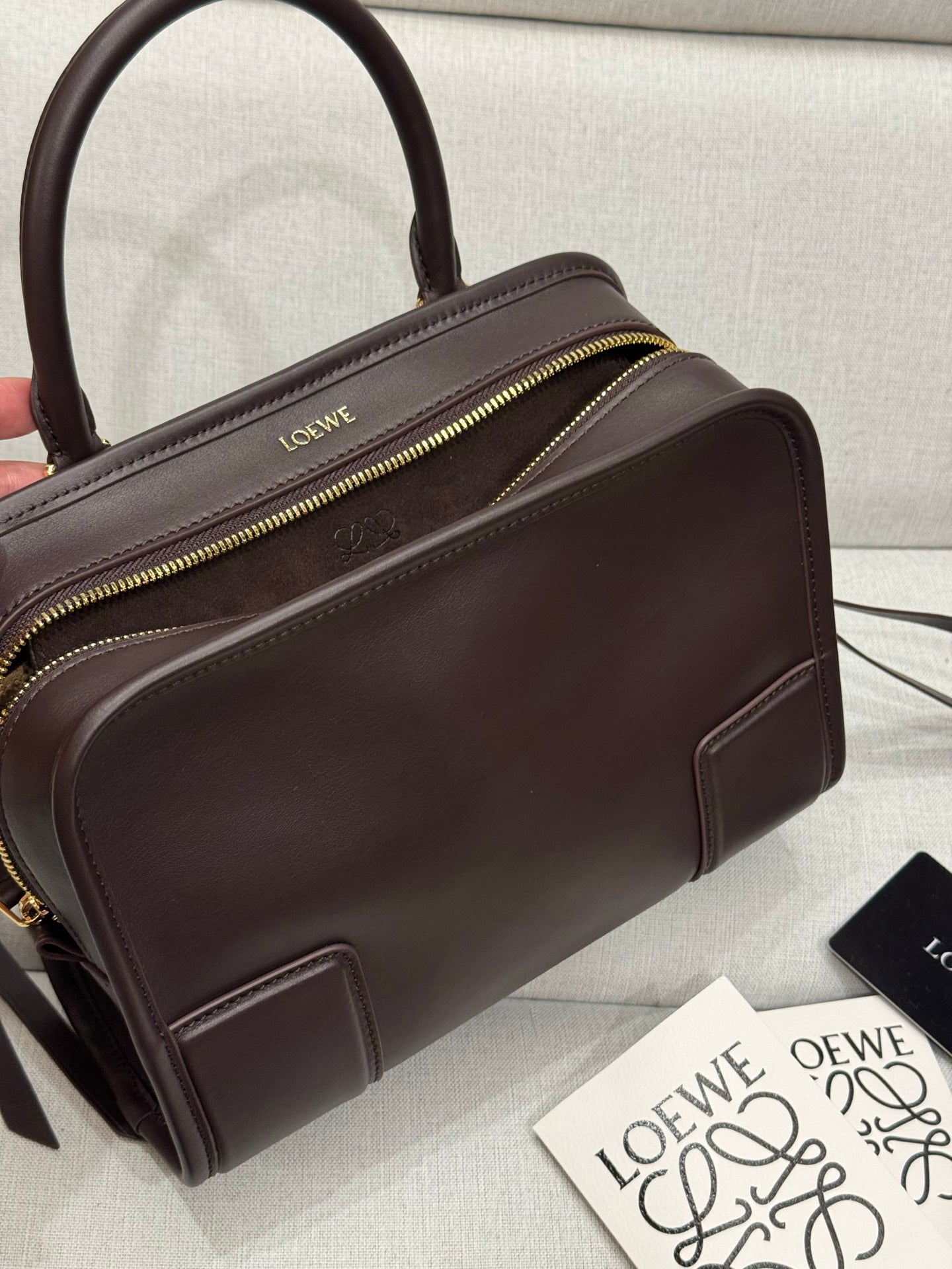 Dark brown leather top-handle bag with gold zipper and front seam details