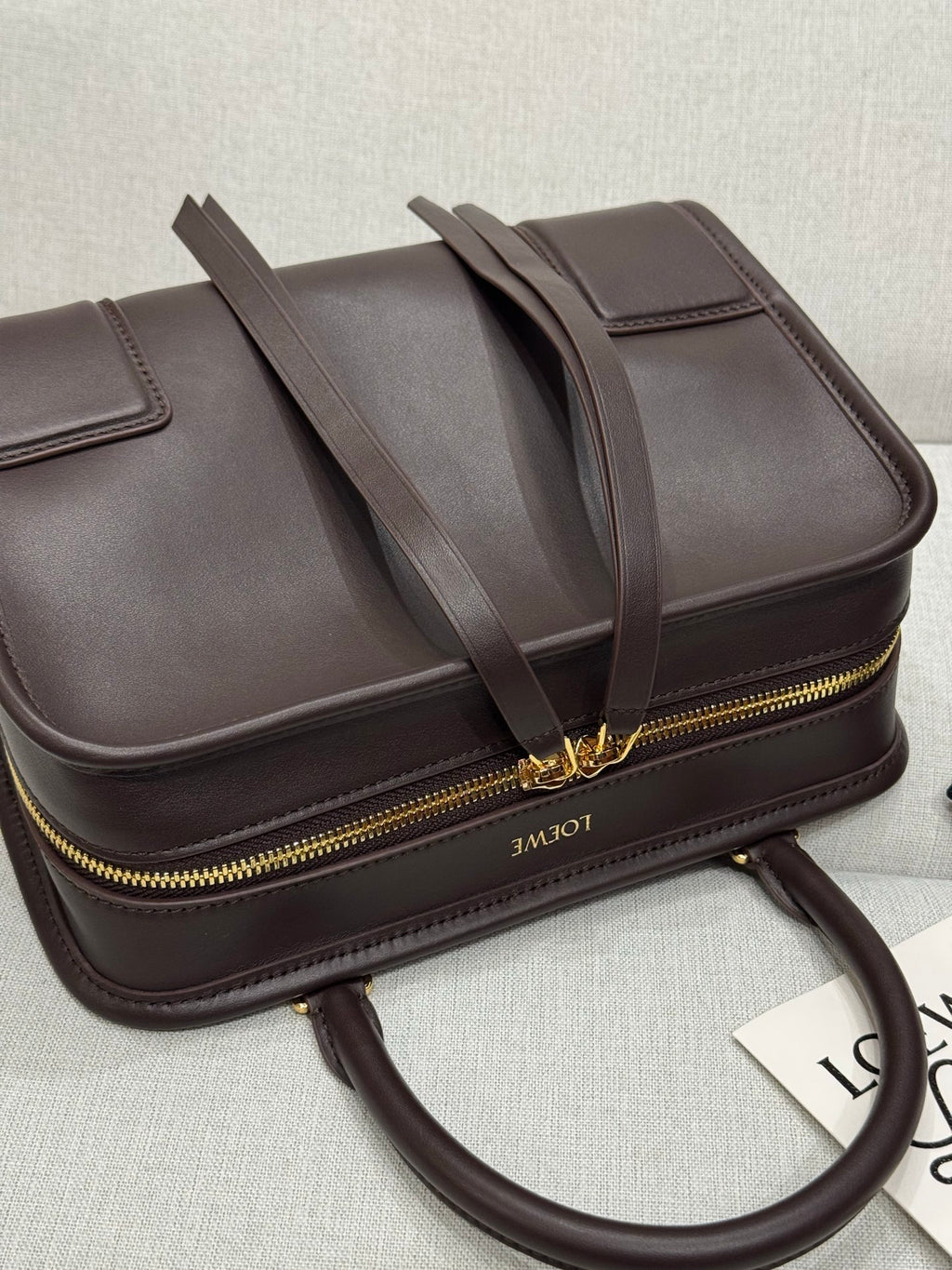 Dark brown leather top-handle bag with gold zipper edge and shoulder strap