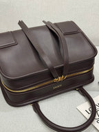 Dark brown leather top-handle bag with gold zipper edge and shoulder strap