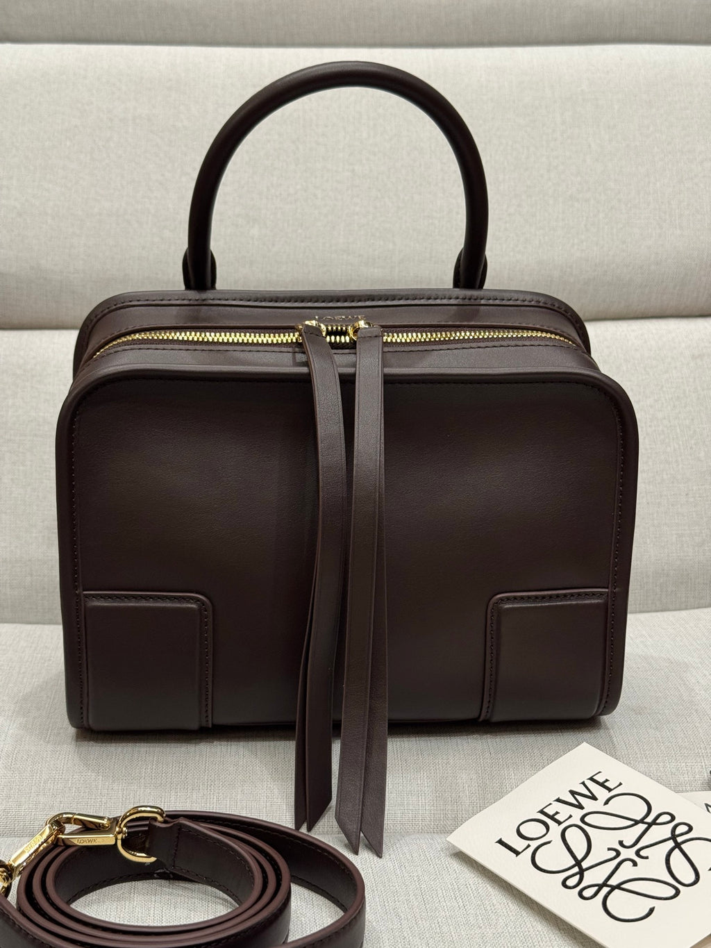 Dark brown leather top-handle bag with gold zip and front patch pockets