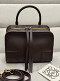 Dark brown leather top-handle bag with gold zip and front patch pockets