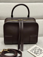 Dark brown leather top-handle bag with gold zip and front patch pockets