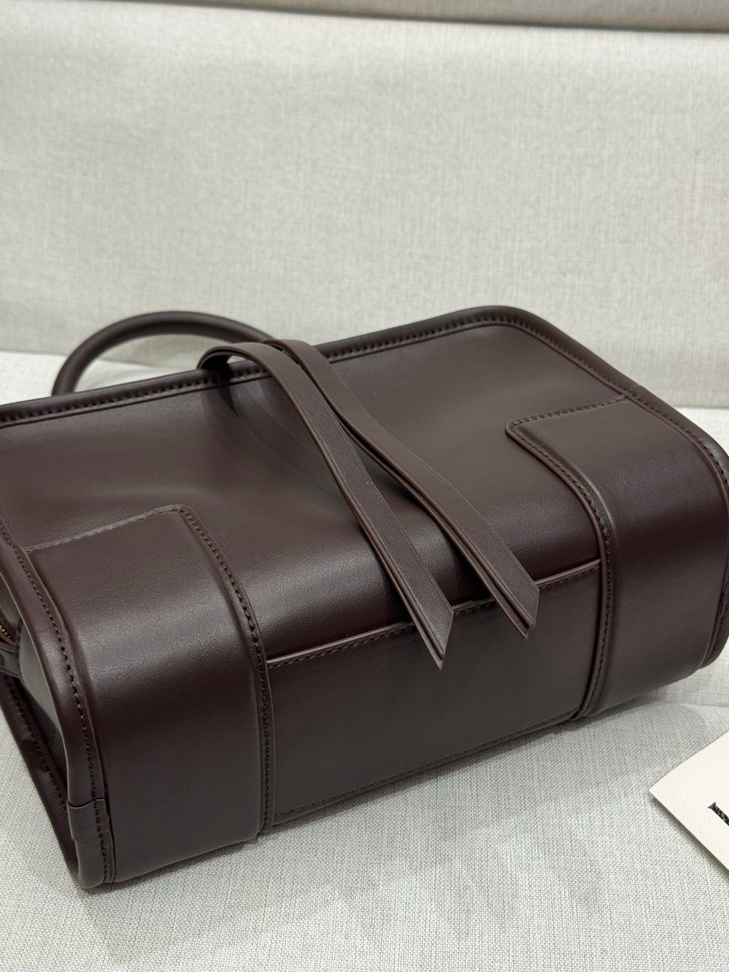 Dark brown leather tote with top handles and stitched panel seams