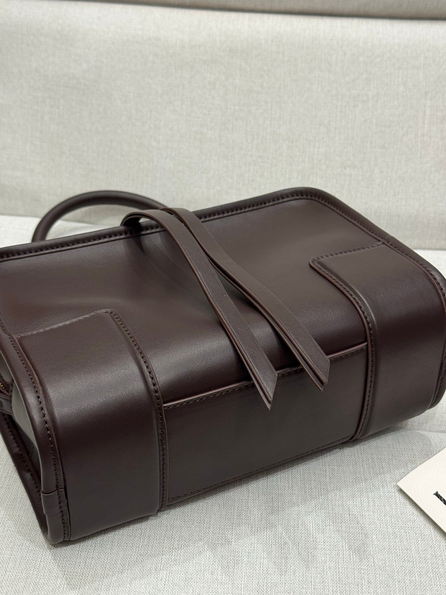 Dark brown leather tote with top handles and stitched panel seams