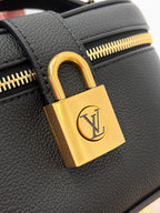Louis Vuitton padlock hardware close-up in gold on dark black textured leather