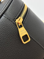 Louis Vuitton gold zipper pull close-up on dark black pebbled leather