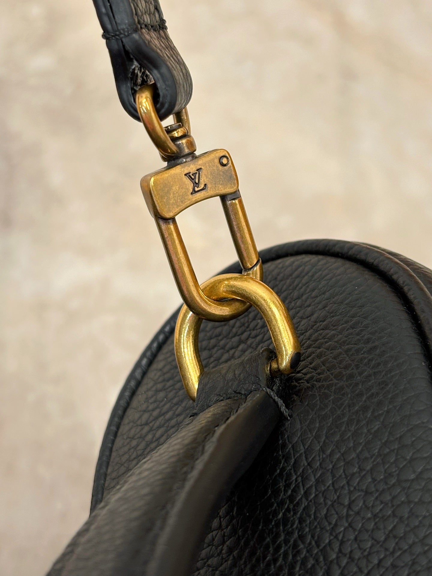Louis Vuitton gold strap clasp hardware on dark black leather bag