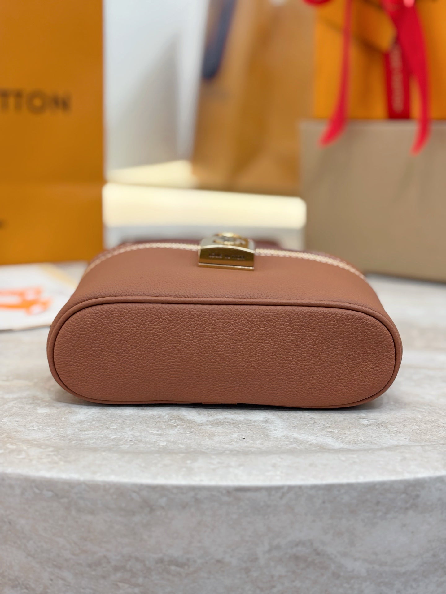 Louis Vuitton brown leather clutch-style bag with rounded top and gold hardware plaque