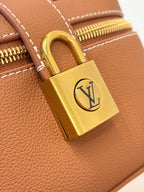 Louis Vuitton brown leather bag padlock with gold clasp and LV logo, close-up
